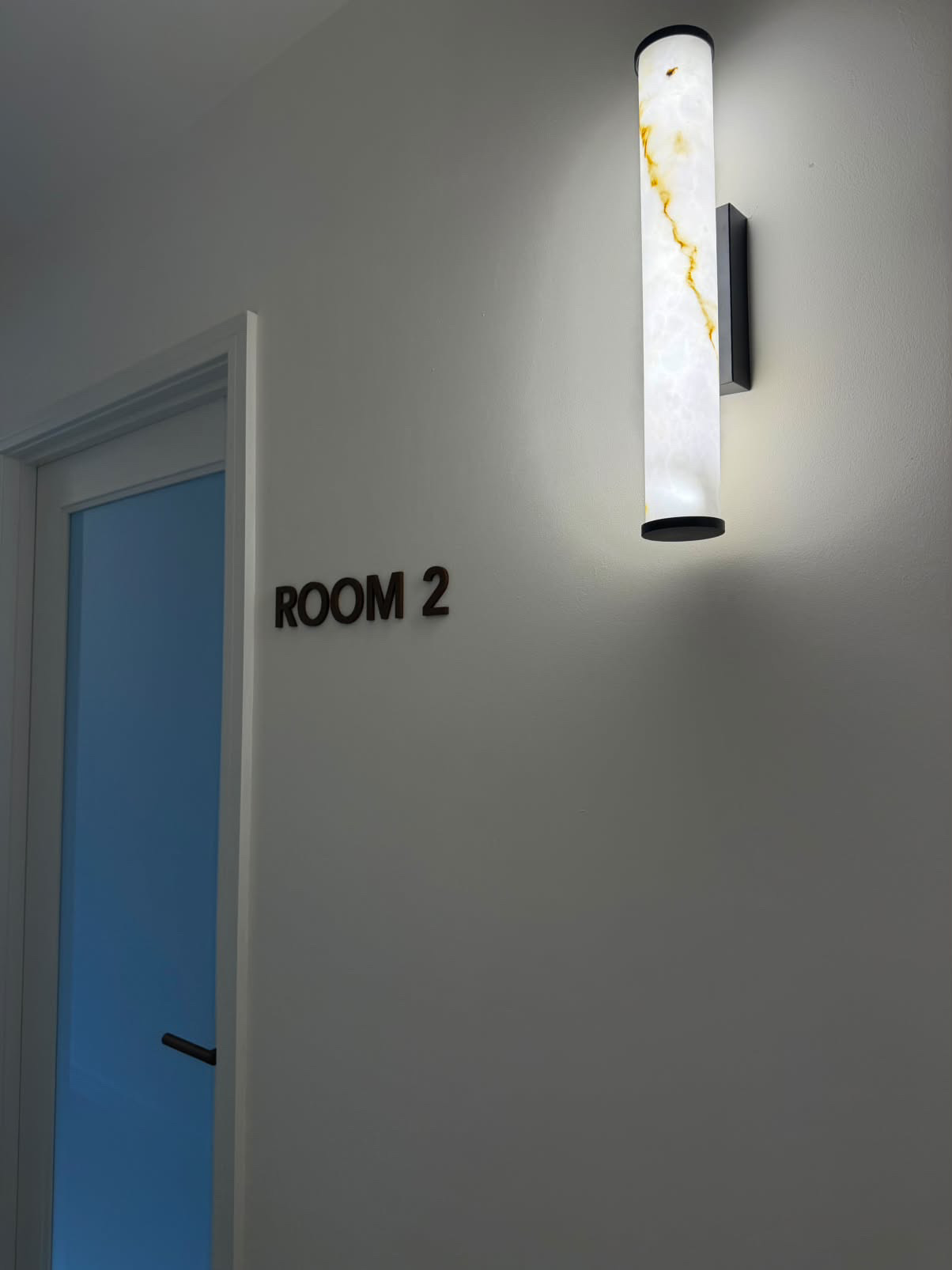Room 2 doorway with a marble-effect wall light