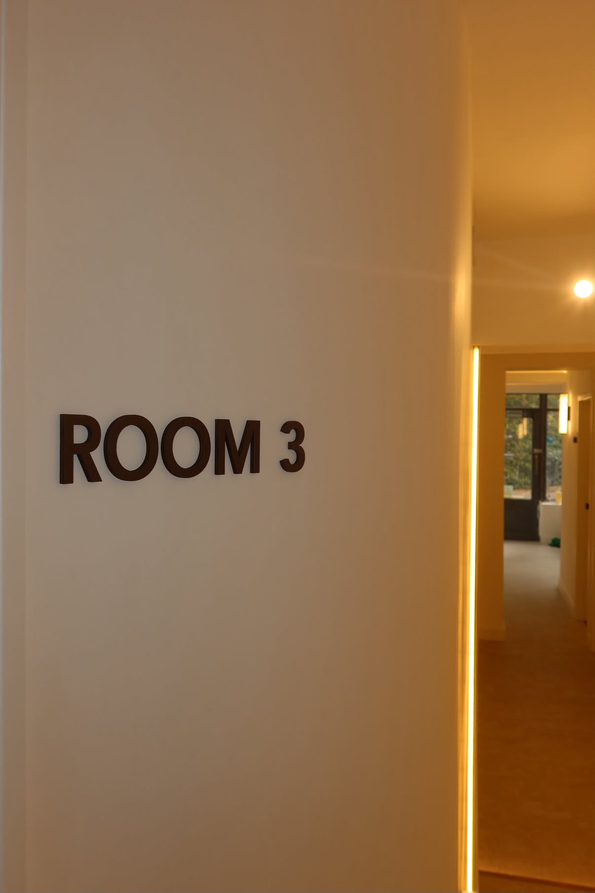 Room 3 signage alongside a warmly illuminated corridor
