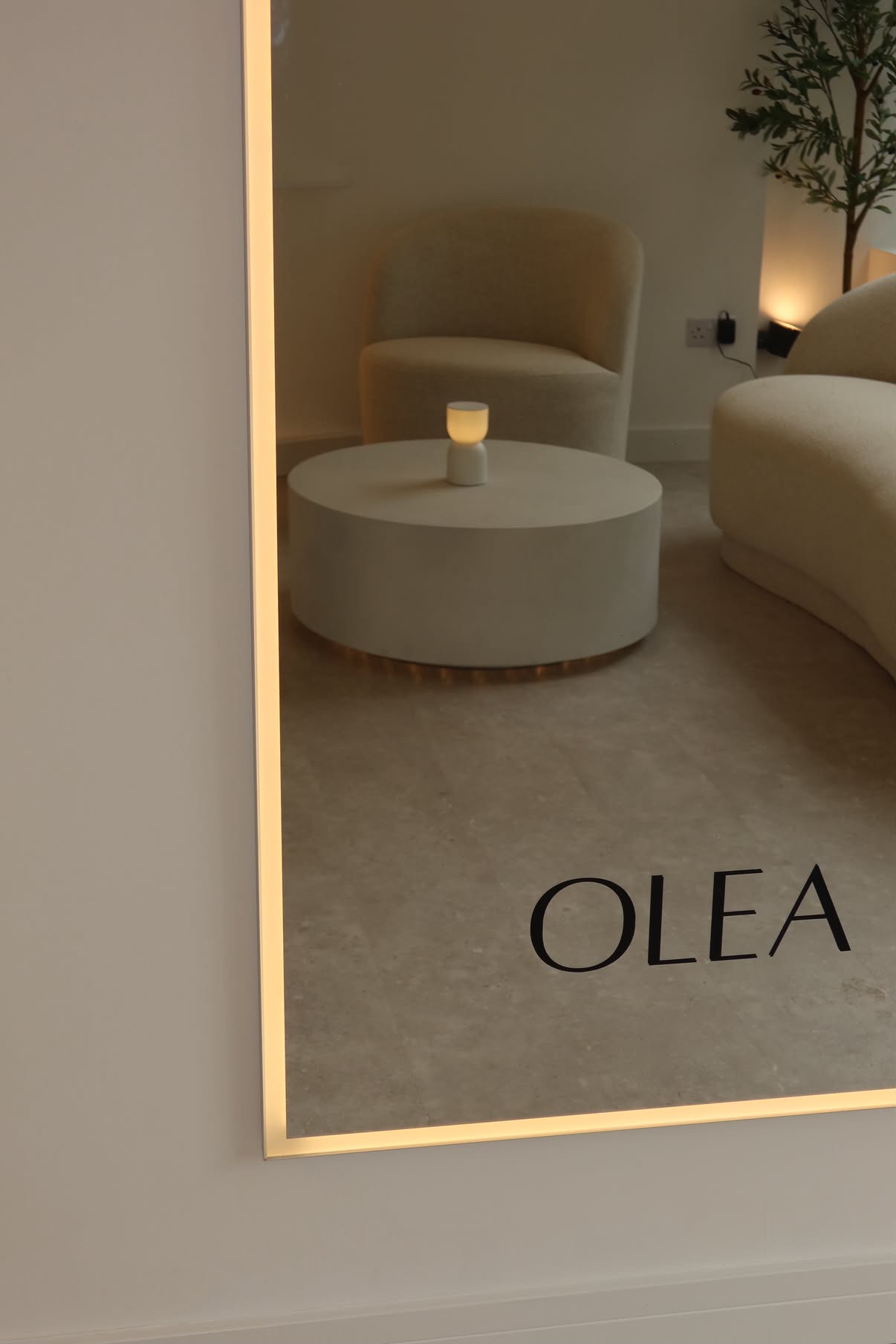 OLÉA illuminated mirror reflecting the calm reception seating