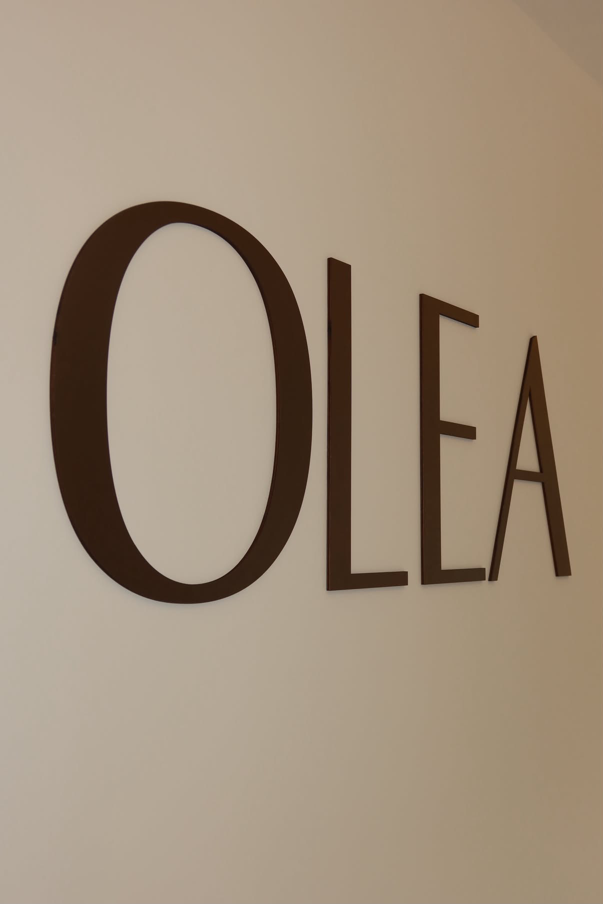 Chocolate brown OLÉA lettering on the reception wall
