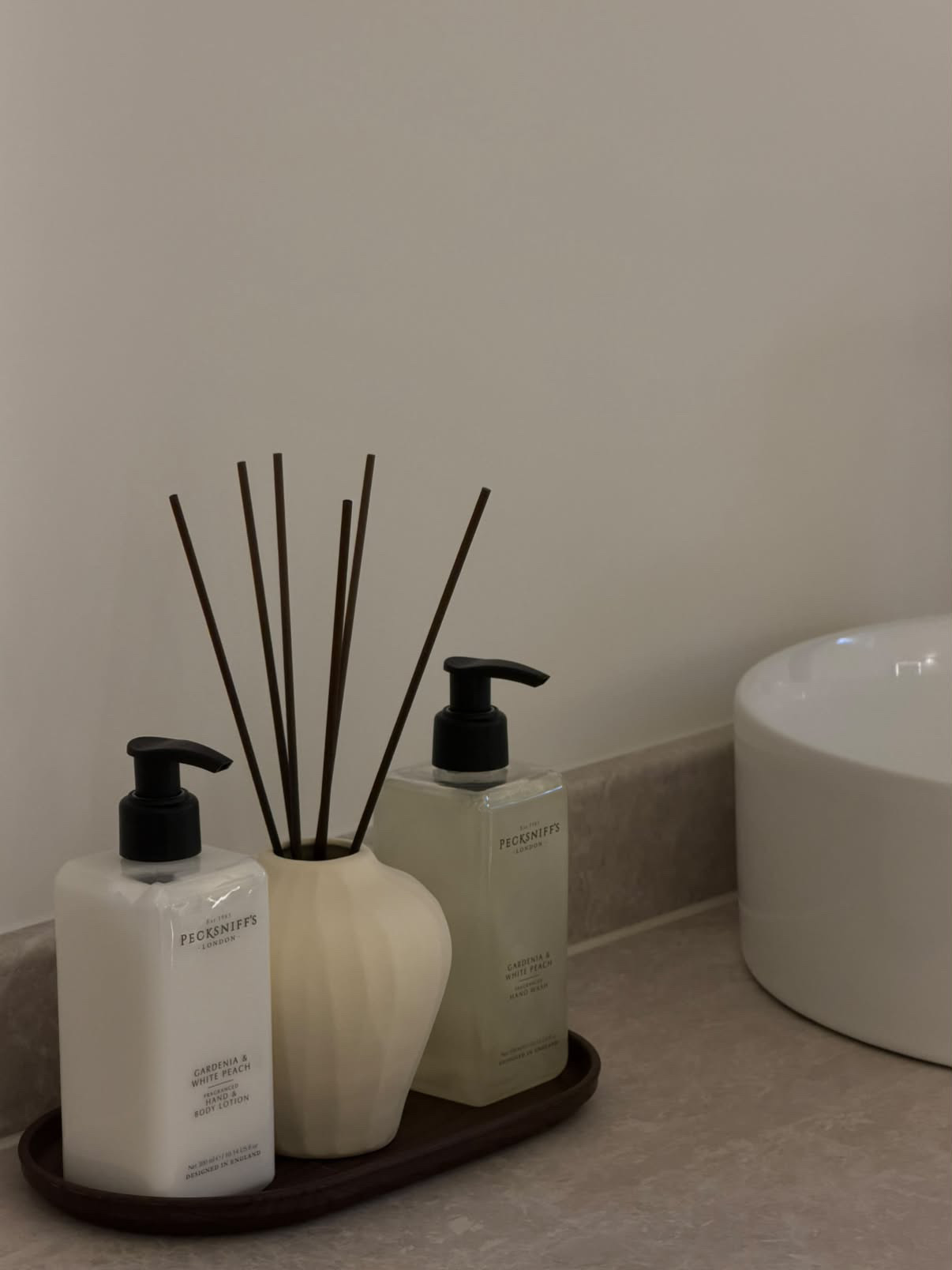 Reed diffuser and hand care bottles beside a white basin at OLÉA